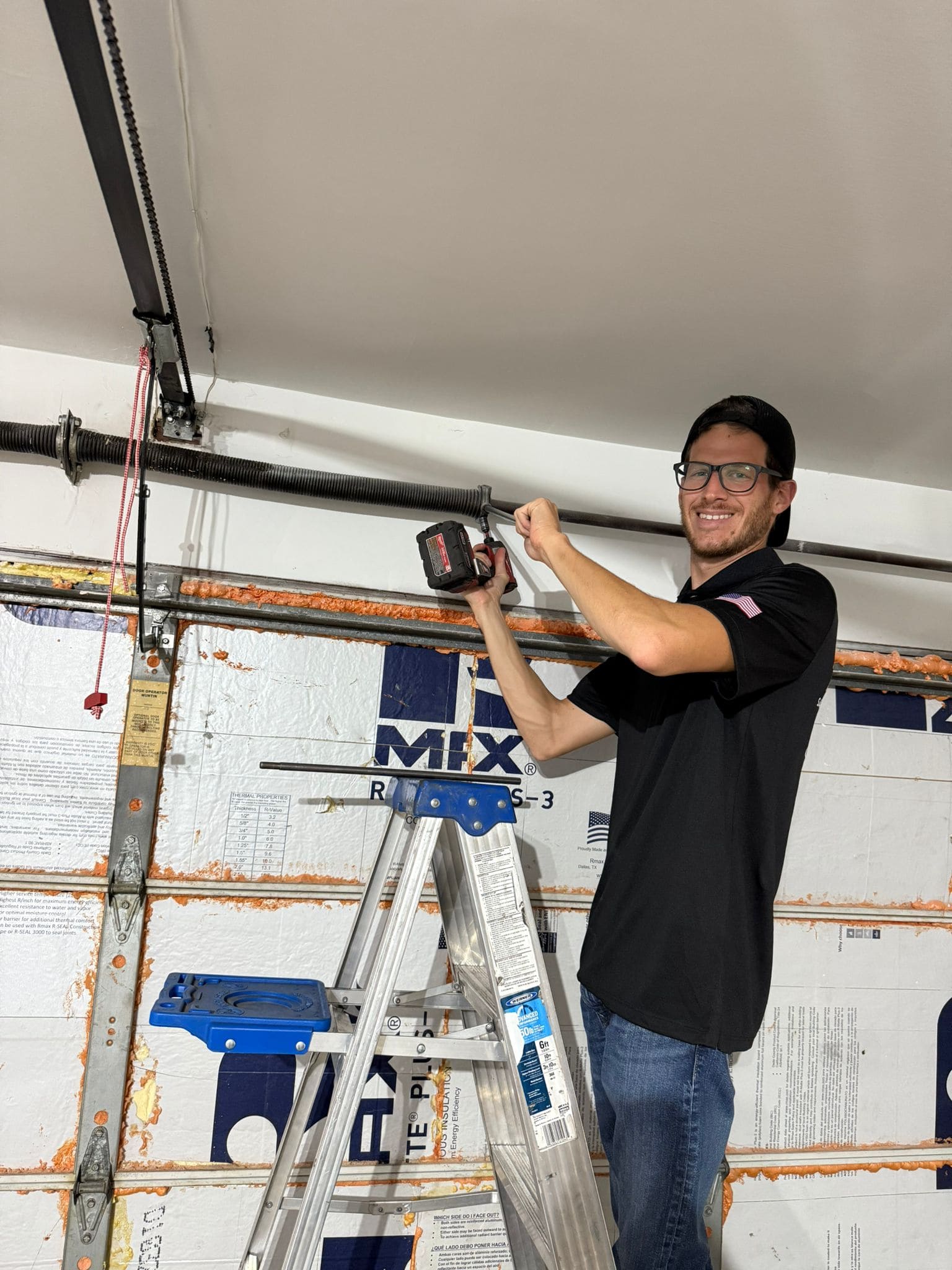 TikTak technician repairing a garage door spring on a ladder