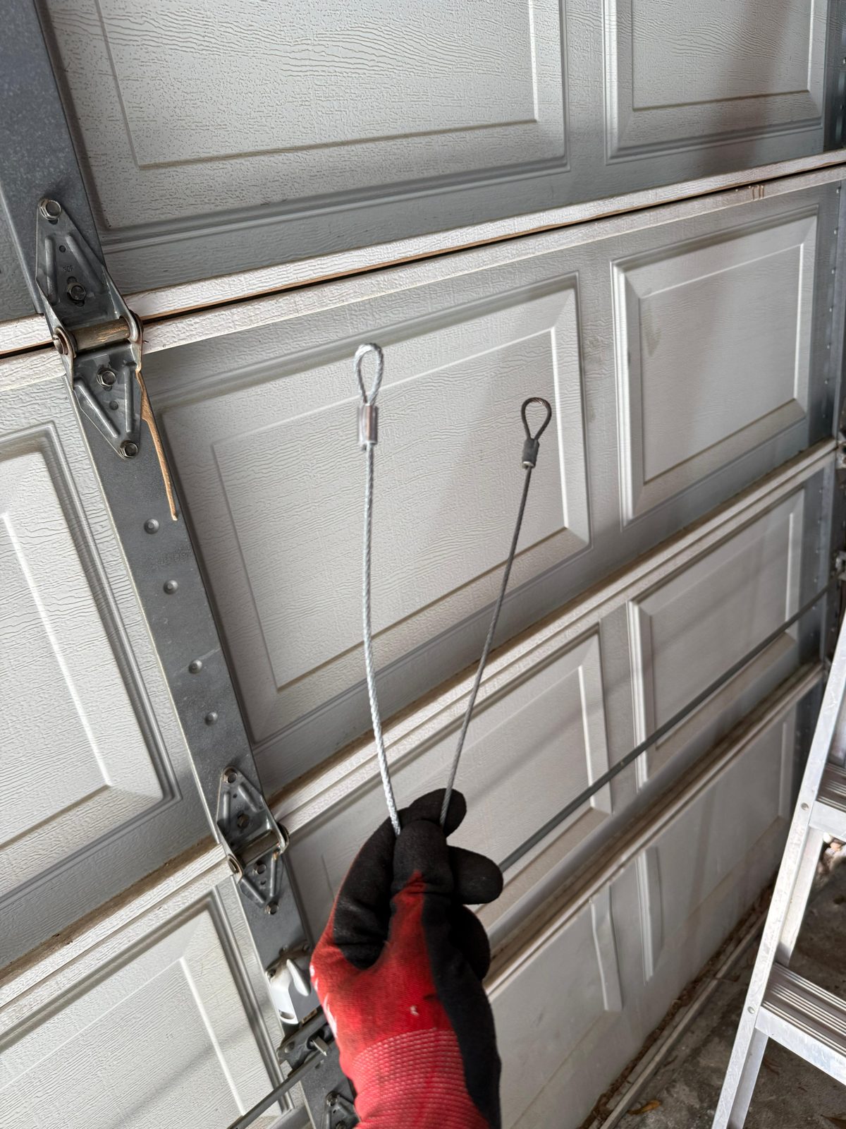 TikTak technician repairing a garage door lift cable in Houston
